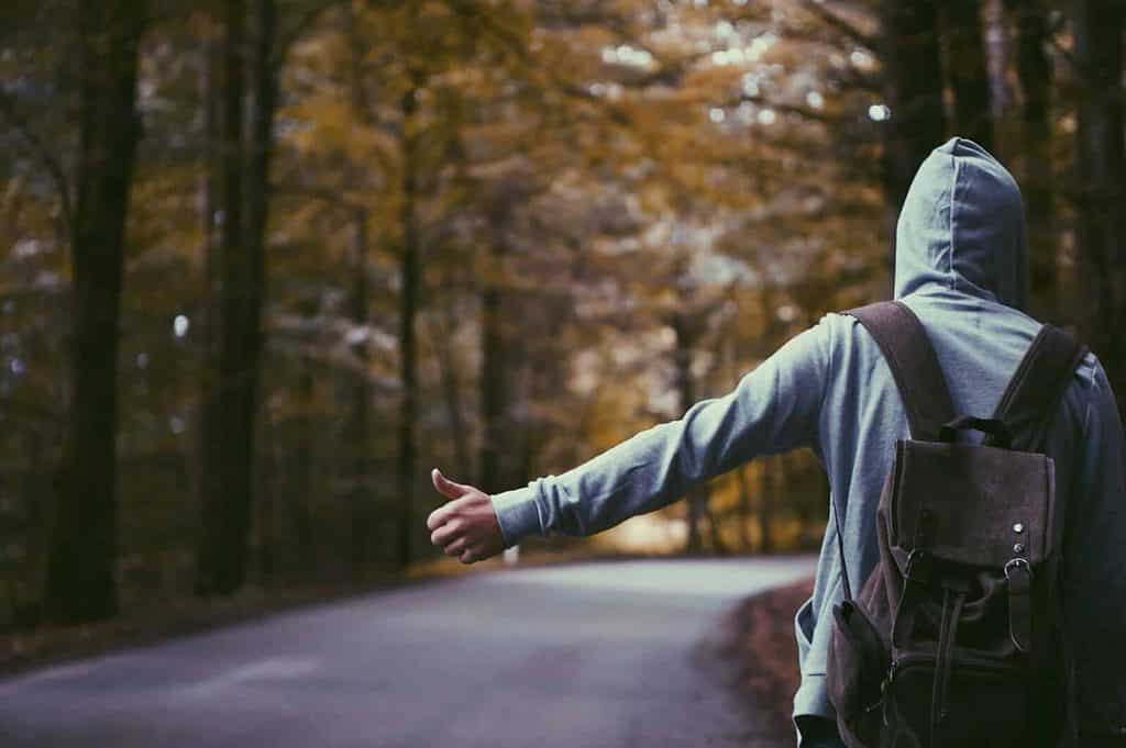A guy hitchhiking wearing a hoodie